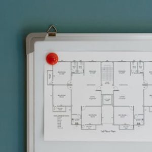 Detailed architectural floor plan pinned on a whiteboard with red magnets.
